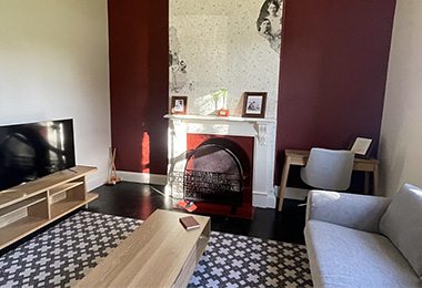 Living room with TV, couch and a feature fireplace.