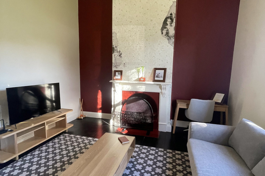 Living room with fireplace, TV, couch and tiled flooring.