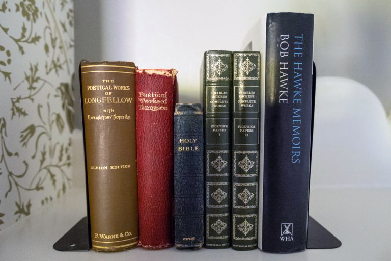 A stack of books relevant to the Hawk House on a shelf.